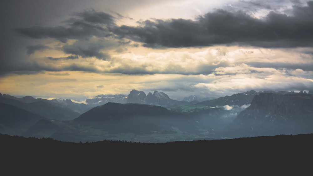 silhouette of mountains under cloudy sky