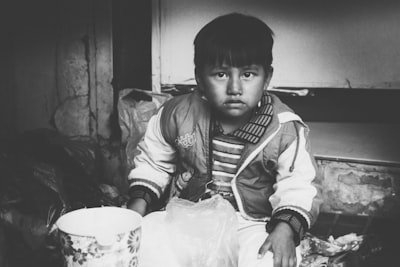 grayscale photo of boy in jacket holding white plastic bag paraguay google meet background