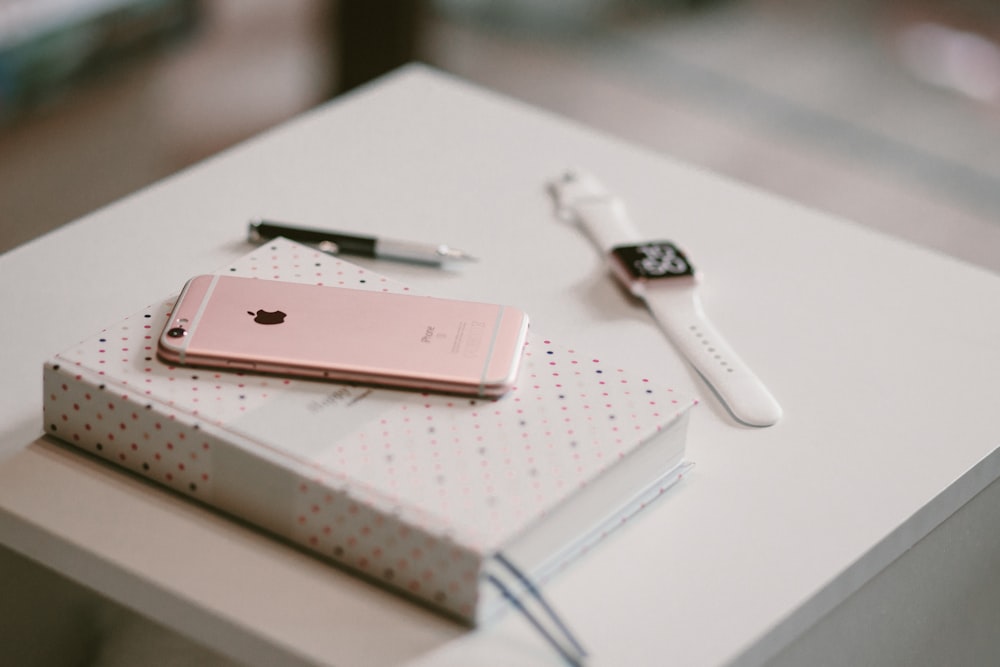 iPhone 6s in oro rosa sul libro vicino all'orologio Apple