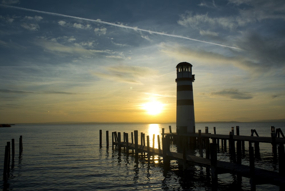 silhouette of lighthouse on sea during sunset