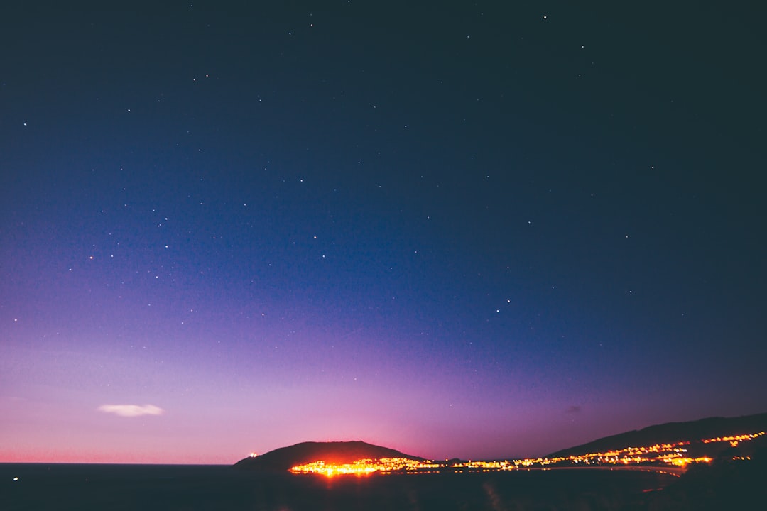 silhouette of buildings and mountain under blue and purple skies