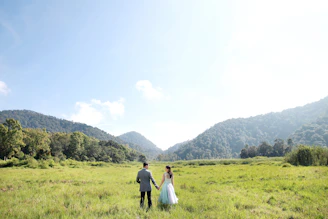 A smiling couple holding hands with a scenic forest background.