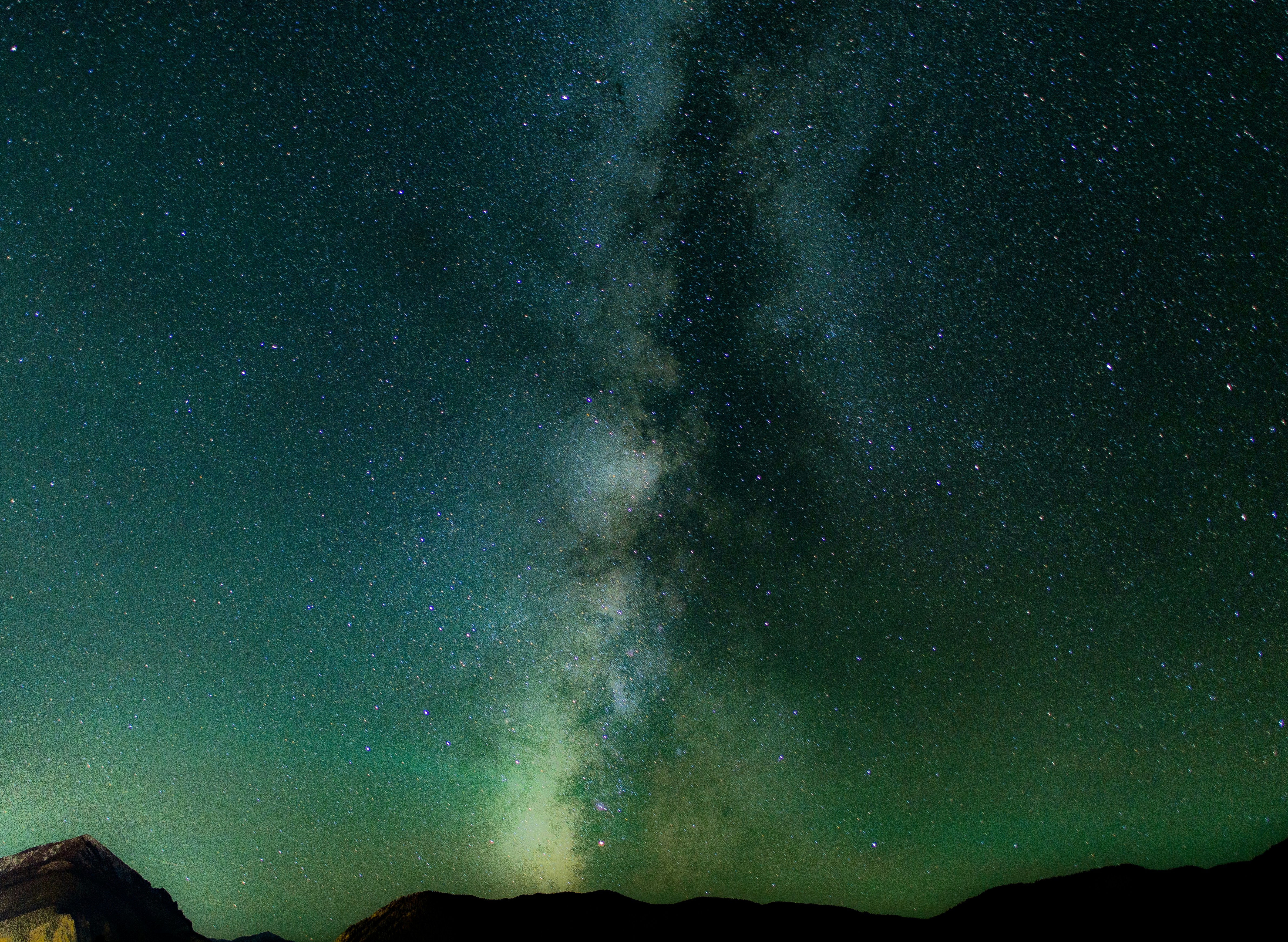 long exposure shot of stars over black mountains milkyway zoom background