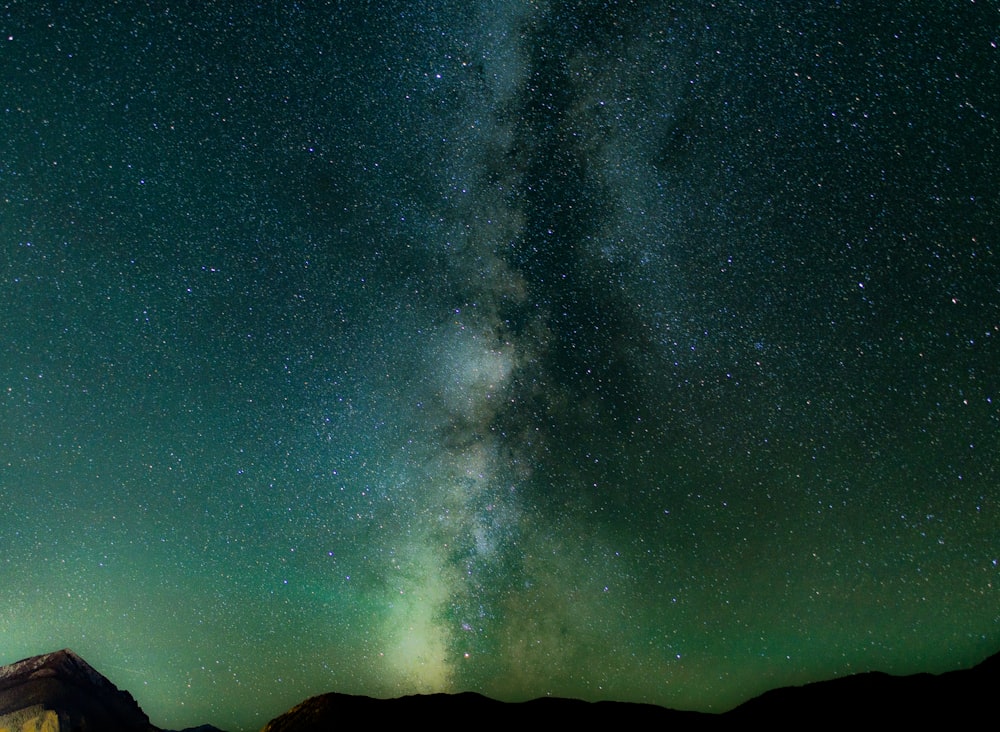 long exposure shot of stars over black mountains