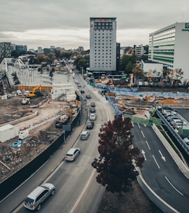 Heavy machinery working on a road infrastructure project surrounded by urban buildings.