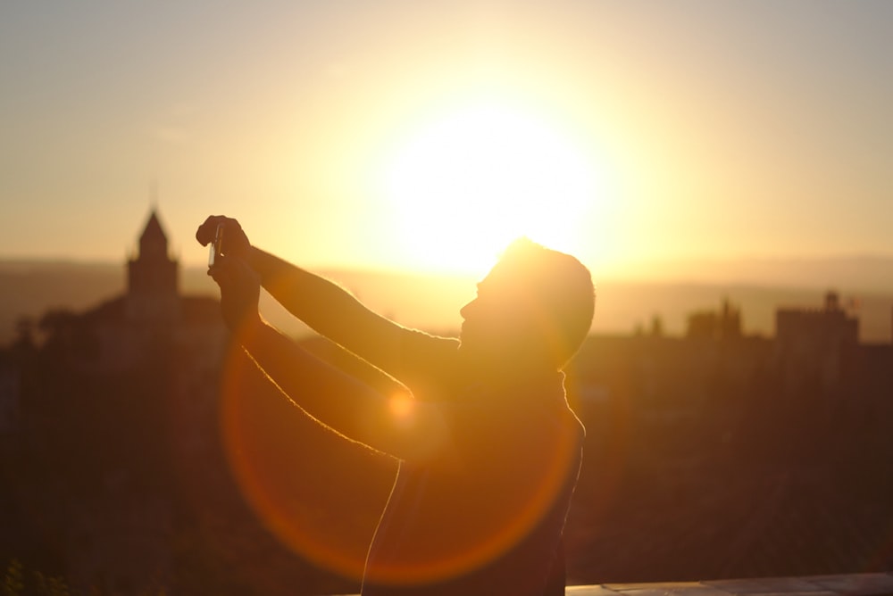 uomo che alza le mani sotto il tramonto