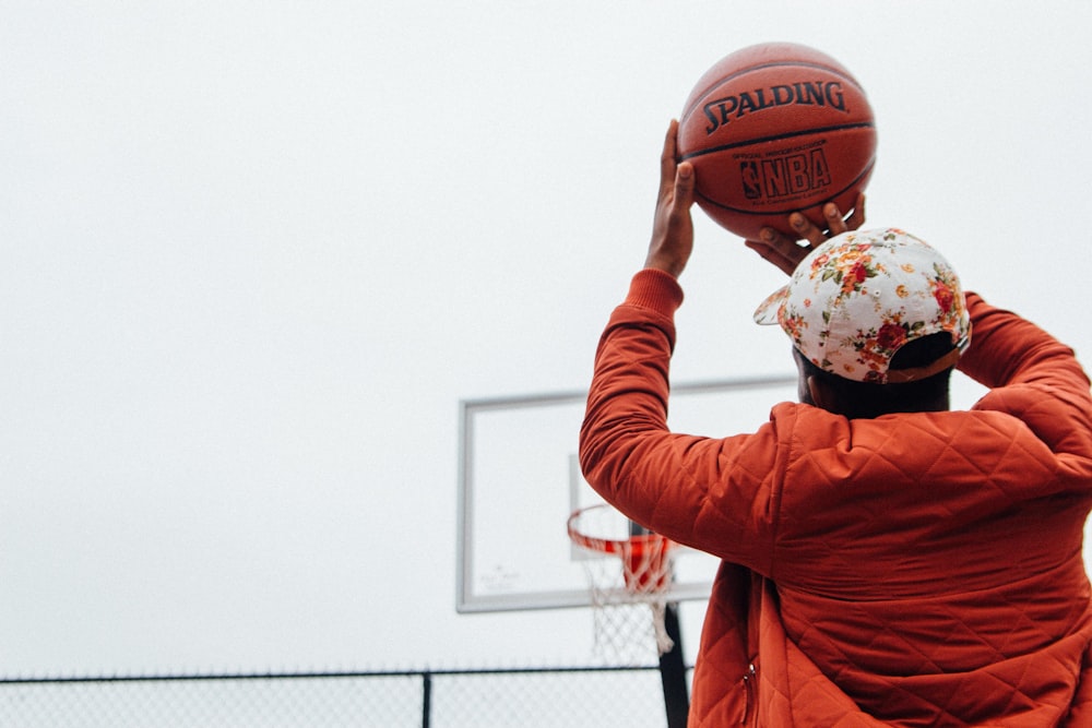person holding basketball looking at basketball hoop system