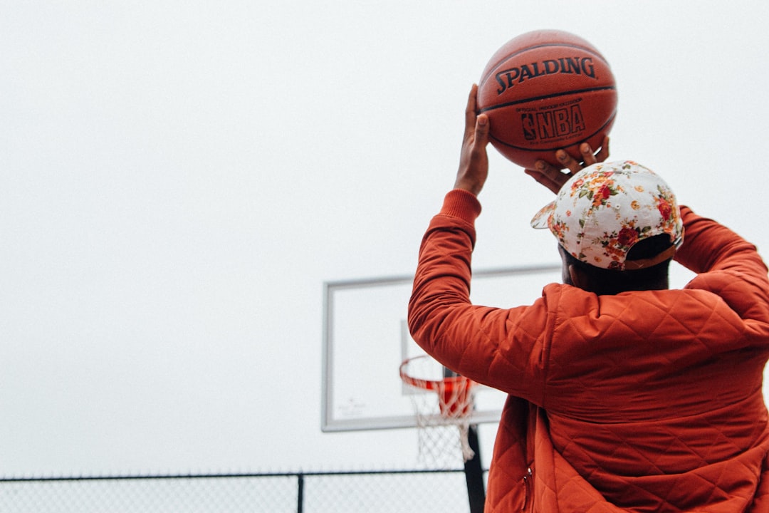 person holding basketball looking at basketball hoop system,
