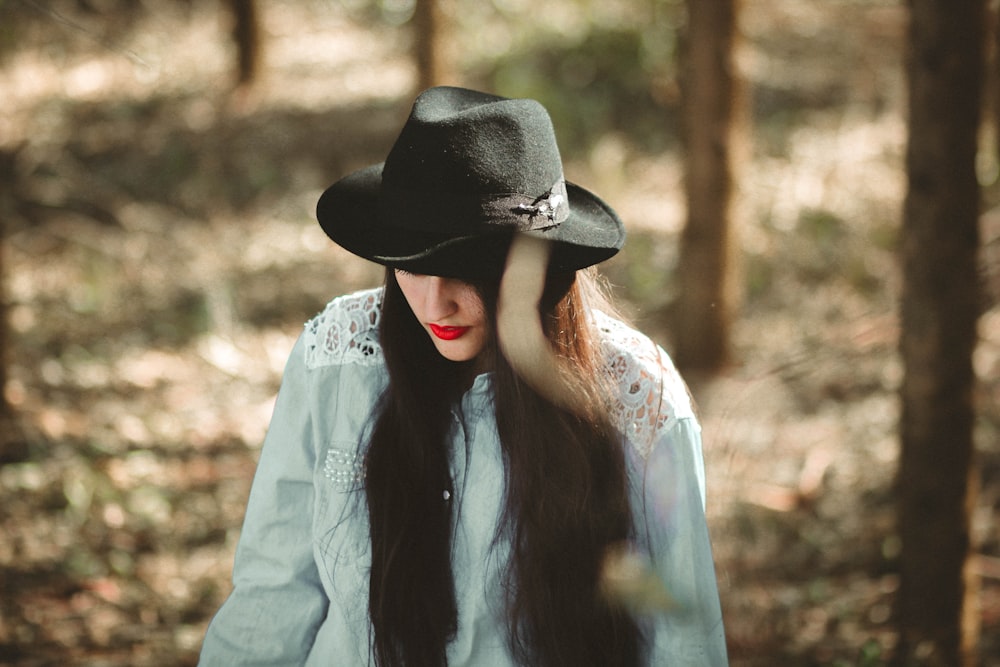 woman wearing blue long-sleeved shirt and black fedora hat