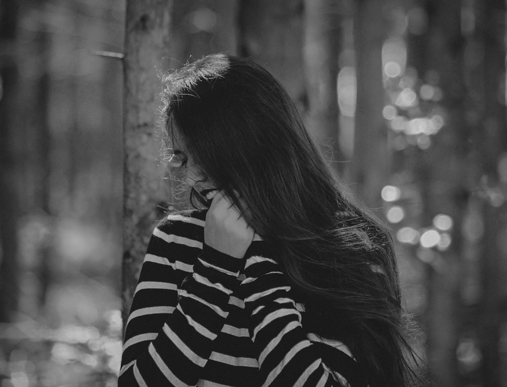 grayscale photography of woman wearing striped sweater standing