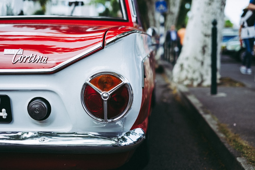 red and white Cortina car parked beside tree