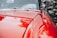 Close-up of a freshly polished red car hood reflecting sunlight.