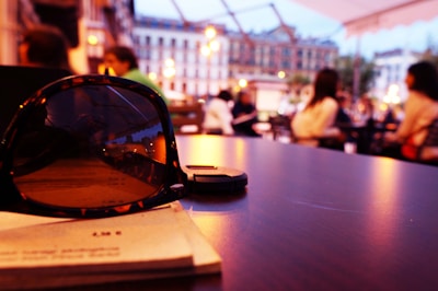 SunBox sunglasses showcased on a sunny outdoor café table with vibrant greenery in the background.
