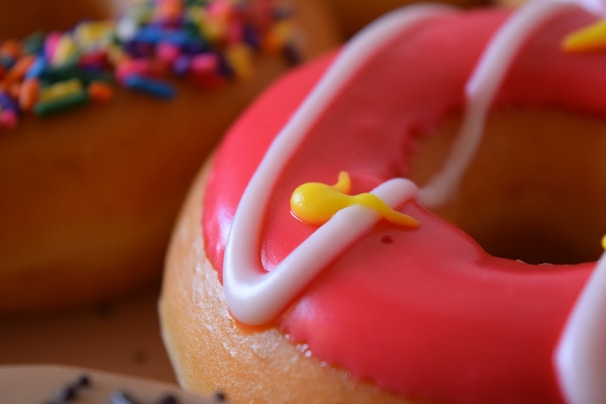 Close-up of a fresh, glazed donut resting on a vibrant pink napkin.