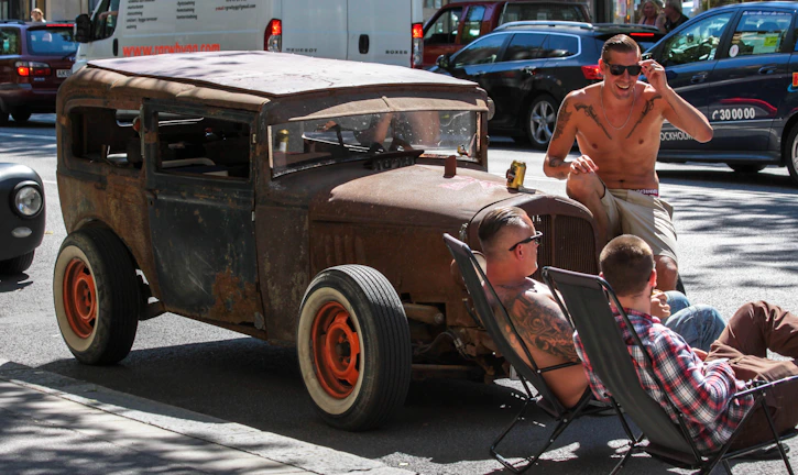Group of diverse drivers chatting and laughing near their cars in a modern city plaza