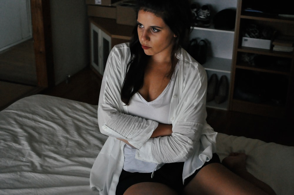 woman wearing white cardigan sitting on bed