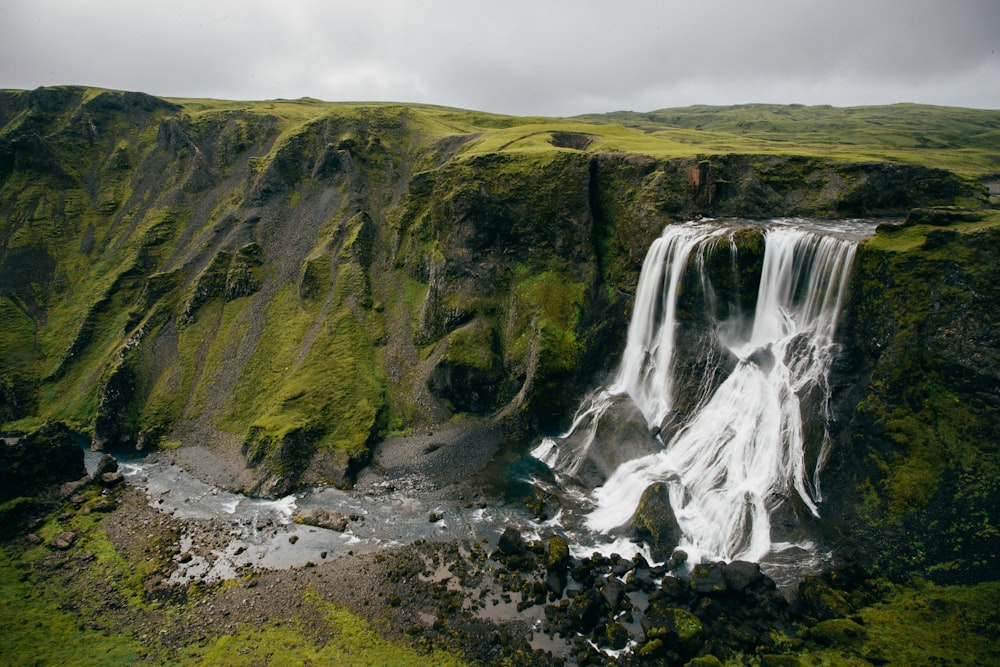 waterfalls beside green mountain