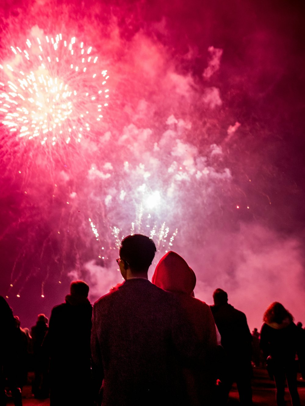 Personas viendo fuegos artificiales durante la noche