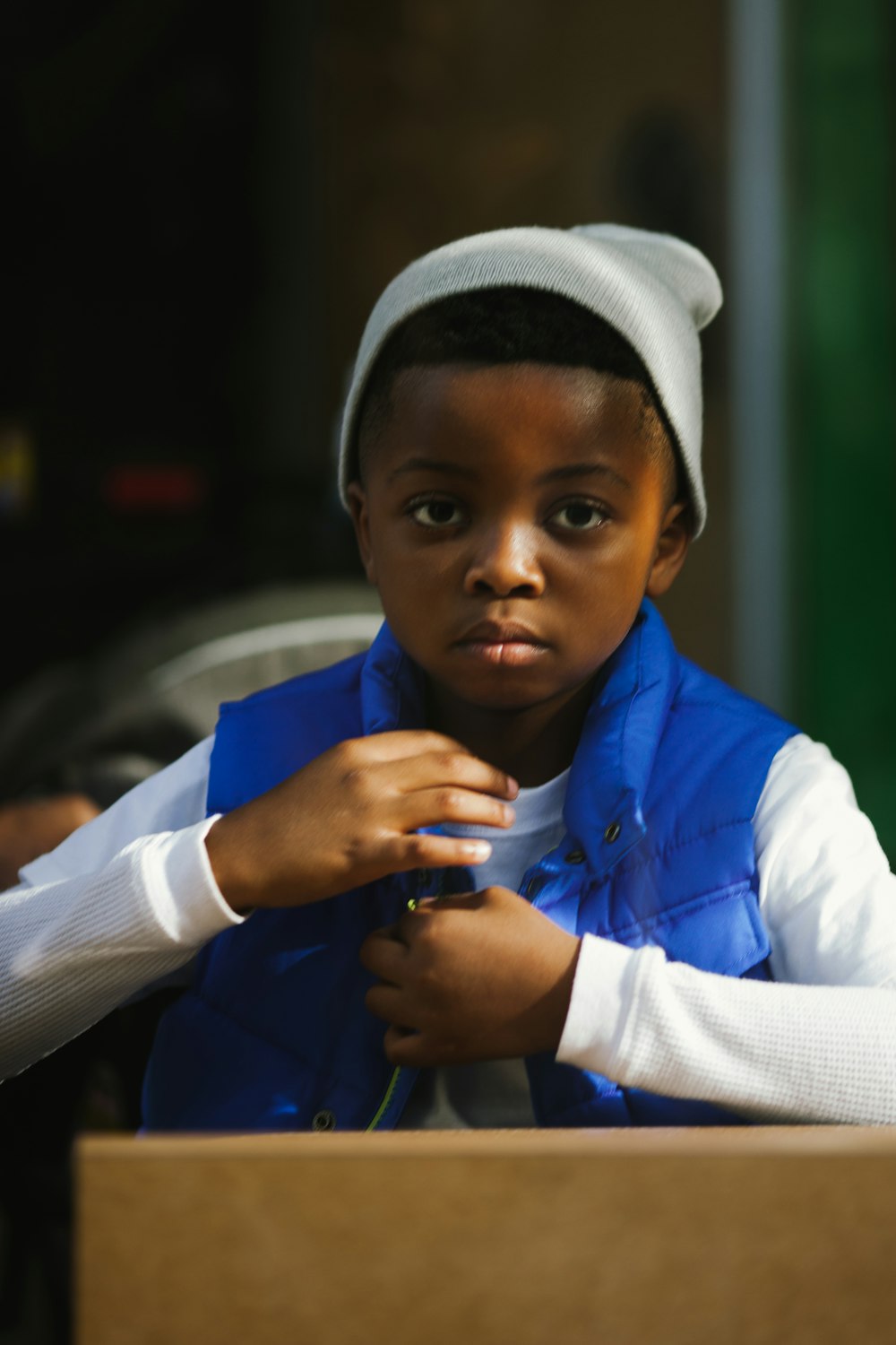 garçon en chemise à manches longues bleue et blanche portant une casquette en tricot blanc et noir