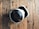 A virtual reality headset with a sleek design rests on a rustic wooden surface, creating a contrast between modern technology and natural textures. The headset is mainly black and white.