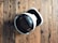 A virtual reality headset with a sleek design rests on a rustic wooden surface, creating a contrast between modern technology and natural textures. The headset is mainly black and white.