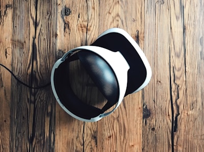 A sleek VR headset resting on a modern desk with a cityscape visible through a window behind it.