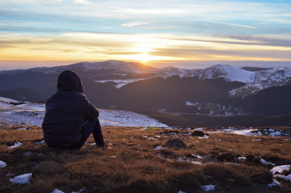 person standing on grass facing on mountain