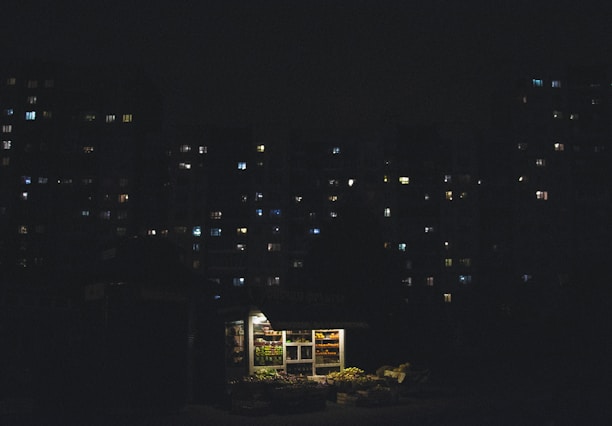 A technician carefully dismantling a kiosk at night under bright work lights.