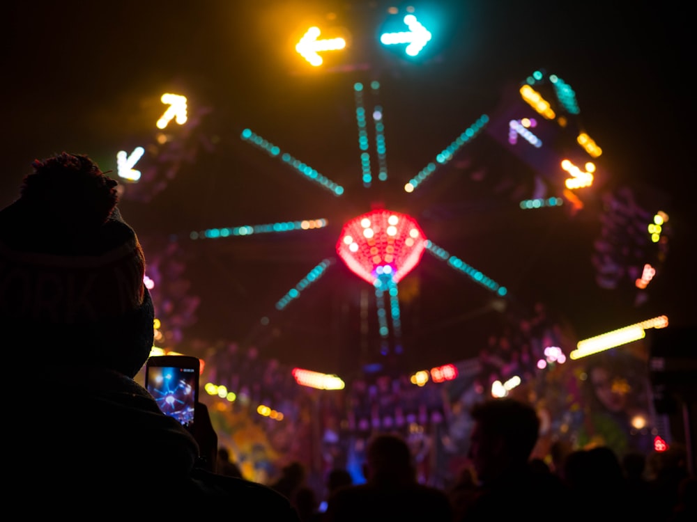 a crowd of people standing around a carnival at night