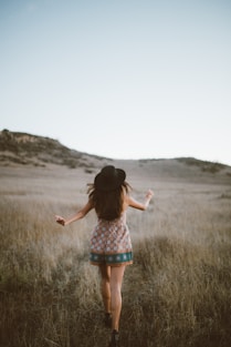 woman wearing brown and green floral romper walking on green grass