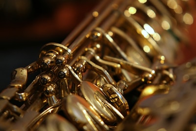 A close-up view of the intricate metal keys and mechanisms of a saxophone, showcasing its shiny gold finish and detailed craftsmanship.