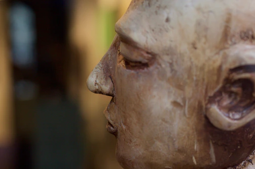 Close-up of a wooden sculpture in progress, showing fine details and textures under warm light.