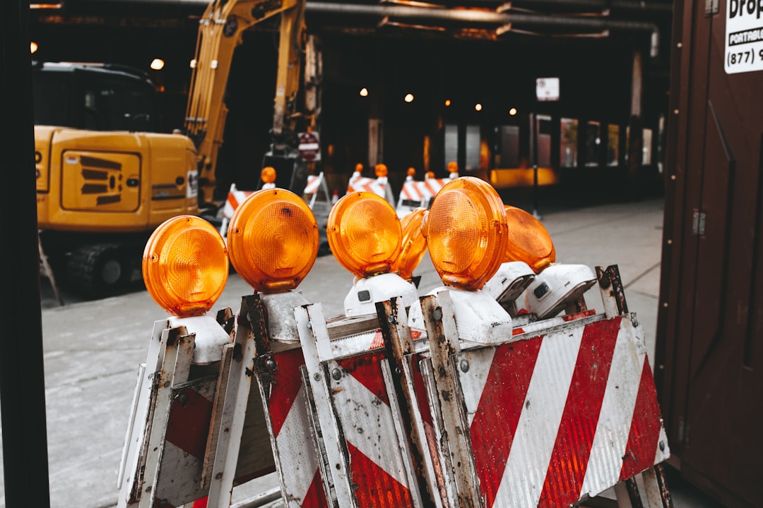 orange lights on top of white and red metal bars, Construction site barricades
