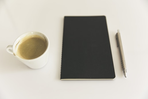 A serene workspace featuring a notebook, pen, and a steaming cup of coffee, symbolizing mindfulness and focus.