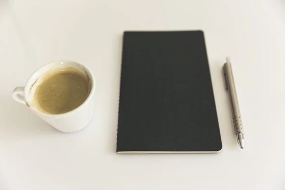 A clean workspace with a notebook, pen, and a simple cup of coffee, embodying minimalism and focus.
