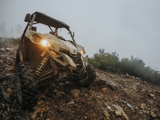A rugged ATV climbing a rocky trail surrounded by lush forest greenery
