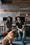 tan dog sitting beside man and woman