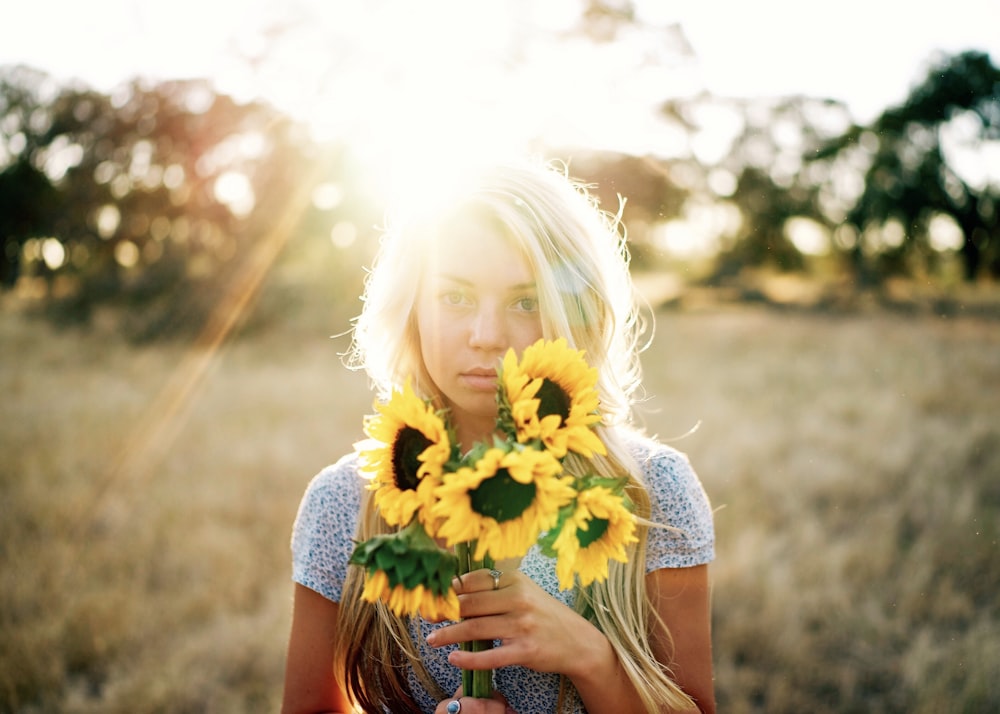 Porträtfotografie einer Frau, die einen Strauß Sonnenblumen hält