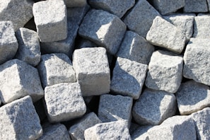 Stack of rough granite blocks in a sunlit warehouse ready for craftsmanship.