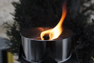 Close-up of a terracotta tea light holder with a flickering candle inside.