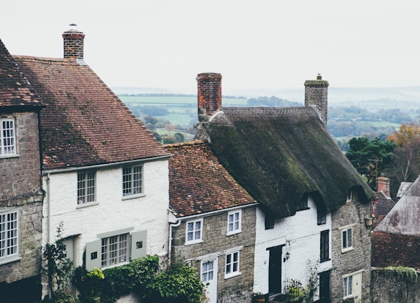 Sunrise over traditional thatched cottages nestled among lush greenery.