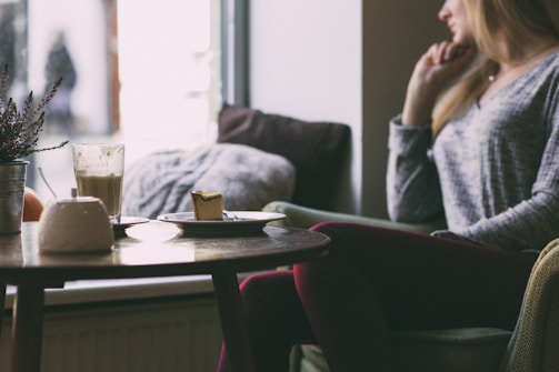 Lifestyle photo of a stylish woman enjoying a slice of marova patisserie cake with a cup of coffee in a chic café setting.