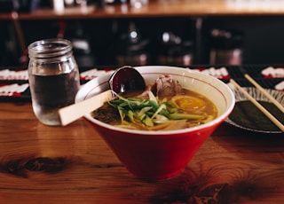 soup with vegetable beside chopsticks and glass of water