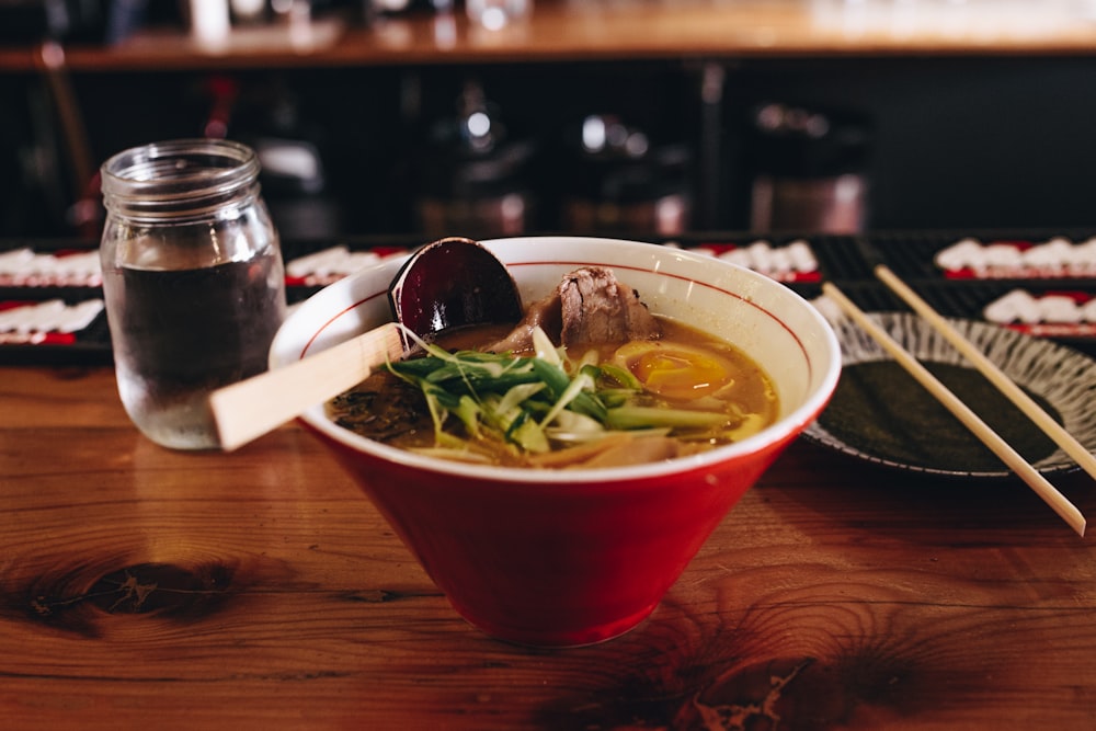 zuppa con verdure accanto bacchette e bicchiere d'acqua