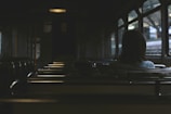 A dimly lit interior of a public transportation vehicle with empty seats and a single passenger sitting alone, gazing out of the window.