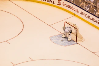 Close-up of a hockey goalie glove resting on ice with a puck nearby.