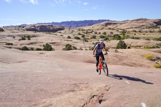 Rider on a dirt bike navigating rocky mountain trails under clear skies