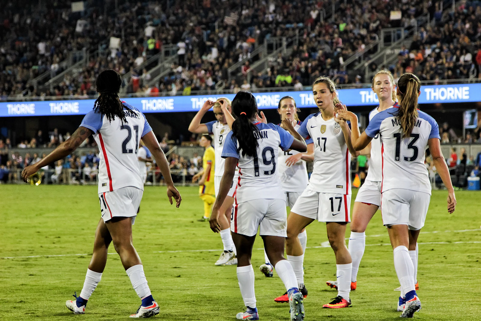 Women's national team soccer players on the pitch in a packed stadium — World Cup atmosphere