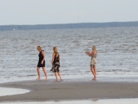 Women walking barefoot along a wild, sandy ocean shore