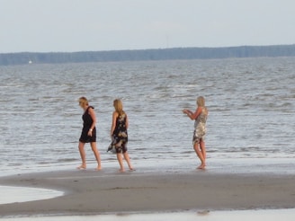 Women walking barefoot along a wild, sandy ocean shore